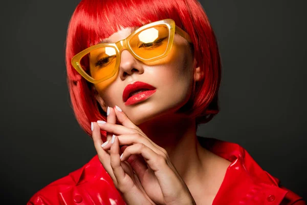 Portrait en gros plan de la jeune femme élégante veste en latex rouge et lunettes de soleil jaune vintage isolé sur gris — Photo de stock