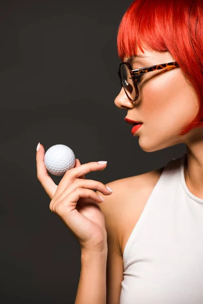 Ritratto ravvicinato di bella giovane donna con taglio bob rosso e occhiali alla moda con palla da golf isolata su grigio — Foto stock