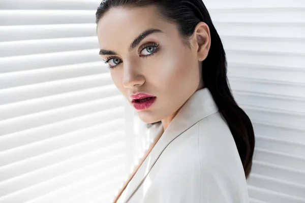 Atractiva modelo joven con maquillaje posando en traje blanco - foto de stock