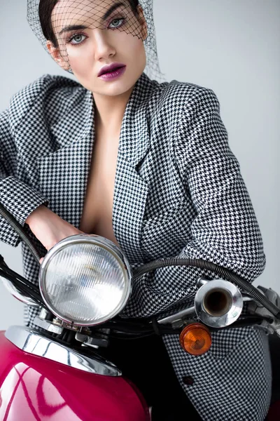 Mulher na moda em jaqueta e véu líquido posando em scooter vintage, isolado em cinza — Fotografia de Stock