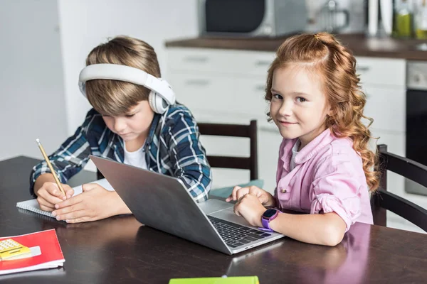 Чарівний маленький брат і сестра роблять домашнє завдання і використовують ноутбук — стокове фото