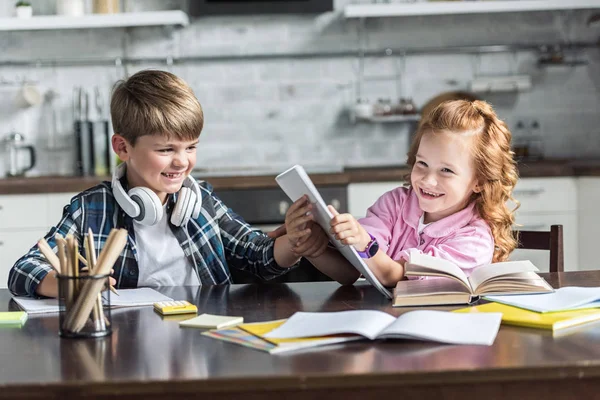 Feliz hermanito y hermana jugando mientras hacen la tarea - foto de stock