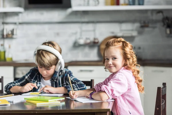 Adorable little kids doing homework together at kitchen — Stock Photo