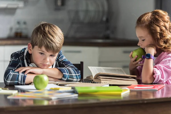 Petit frère et soeur avec des pommes vertes faisant leurs devoirs — Photo de stock