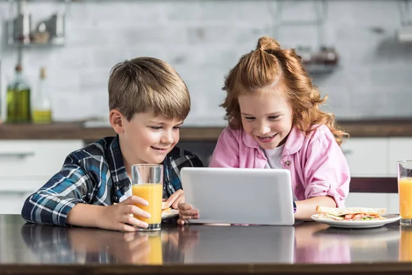 Smiling little brother and sister using tablet during breakfast — Stock Photo