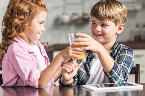 Маленький брат і сестра пропускають склянку апельсинового соку на кухні — стокове фото