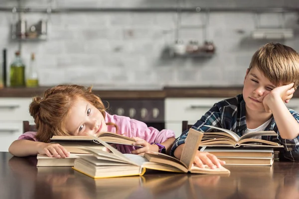 Tired little scholars sleeping on book while doing homework — Stock Photo