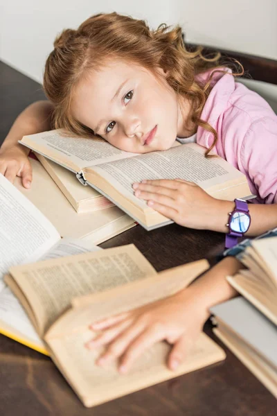 Vue grand angle de la petite écolière épuisée couchée sur des livres — Photo de stock