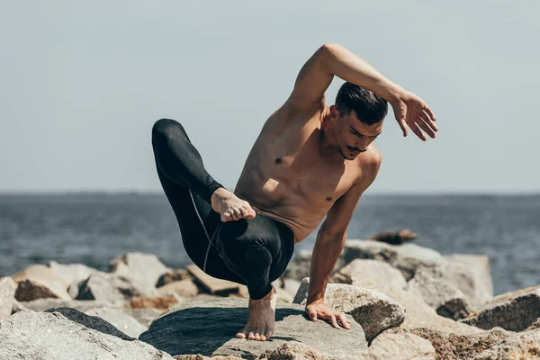 Handsome shirtless man performing contemporary dance on rocky coast — Stock Photo