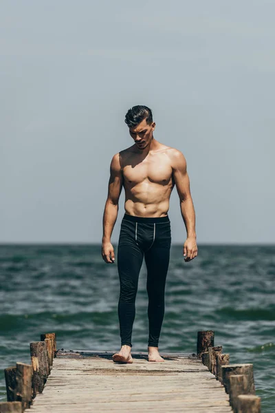 Bel homme sportif debout sur une jetée en bois — Photo de stock