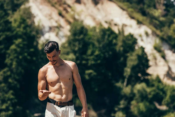 Hombre sin camisa guapo mirando su mano - foto de stock