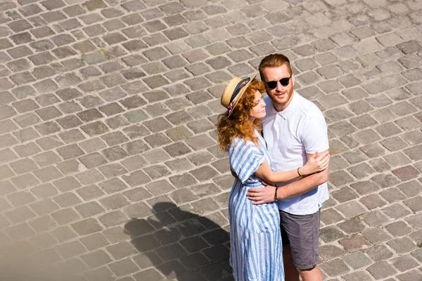 Redhead man in sunglasses embracing girlfriend at city street — Stock Photo