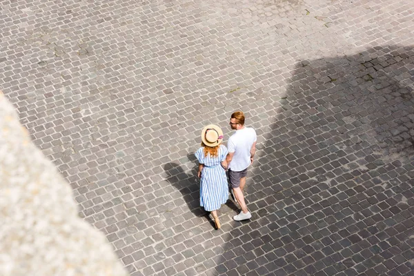 Vue grand angle du couple rousse tenant la main et marchant dans la rue de la ville — Photo de stock