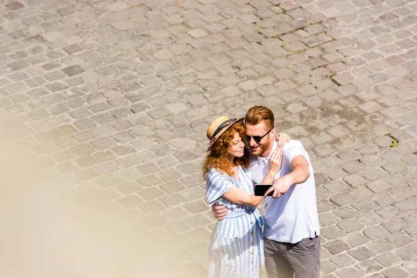 Happy redhead couple taking selfie on smartphone at urban street — Stock Photo