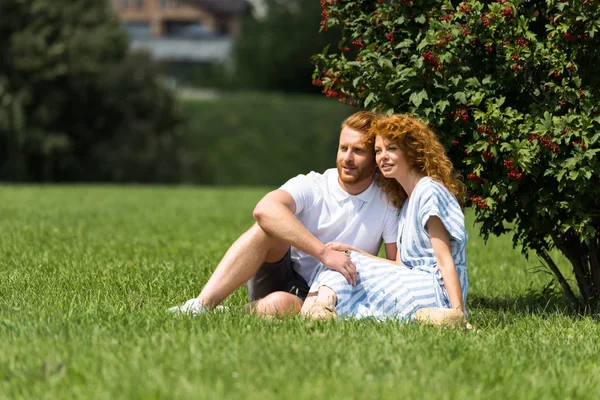 Felice rossa coppia seduta su erba nel parco — Foto stock