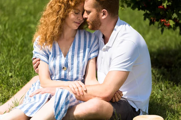 Rossa coppia con gli occhi chiusi che si abbracciano su erba nel parco — Foto stock