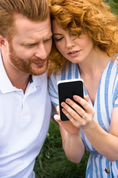 Redhead woman showing smartphone to boyfriend outdoors — Stock Photo