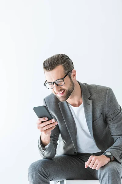 Elegante uomo elegante in abito grigio con smartphone, isolato su bianco — Foto stock