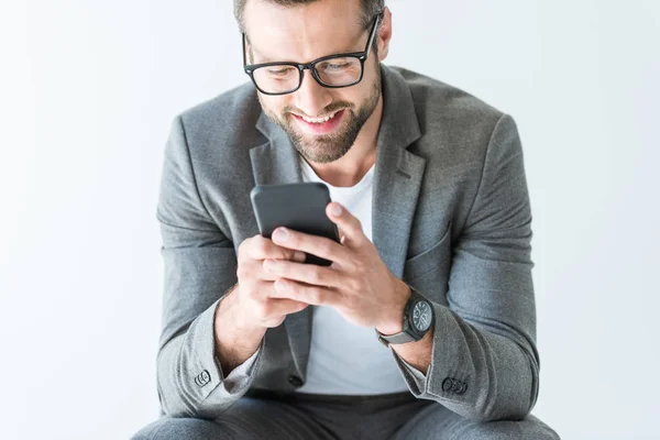 Bel homme souriant en costume gris avec smartphone, isolé sur blanc — Photo de stock