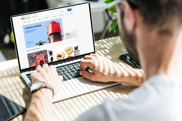 Ausgeschnittene Ansicht eines Mannes mit Laptop und ebay-Website auf dem Bildschirm — Stockfoto