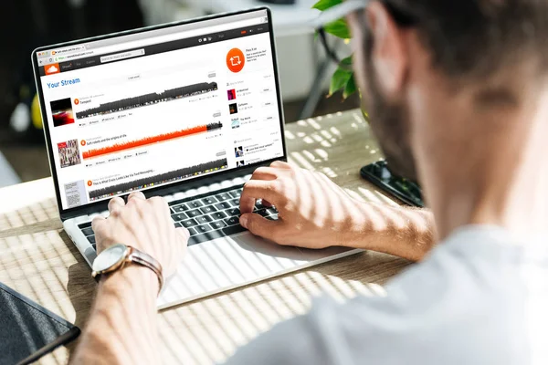 Back view of man using laptop with soundcloud website on screen — Stock Photo