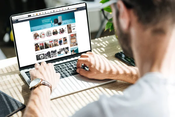 Back view of man using laptop with amazon website on screen — Stock Photo