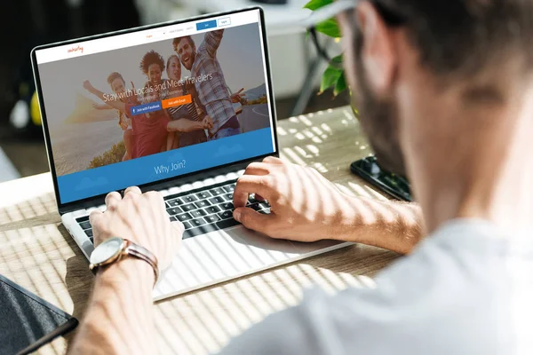 Vista ritagliata dell'uomo utilizzando computer portatile con sito web couchsurfing sullo schermo — Foto stock