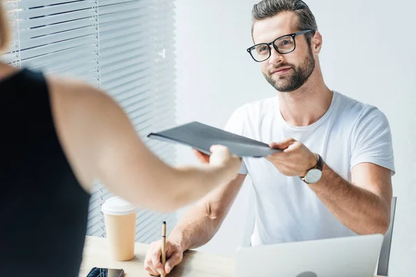 Hombre de negocios guapo dando documentos a colega en la oficina moderna — Stock Photo