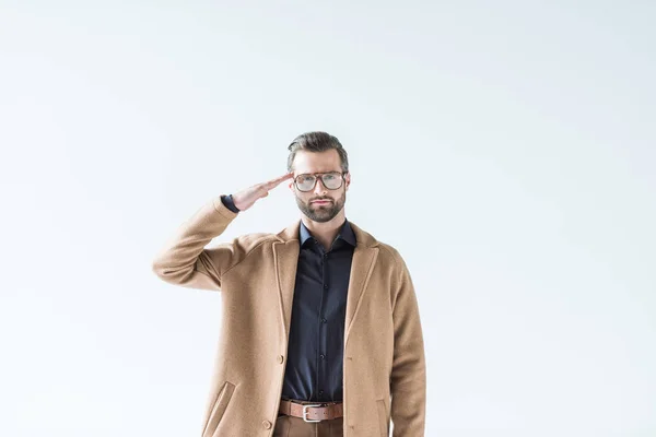 Handsome man in brown coat saluting and looking at camera, isolated on white — Stock Photo