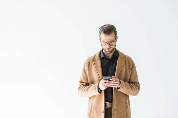 Bel homme en manteau marron avec smartphone, isolé sur blanc — Photo de stock