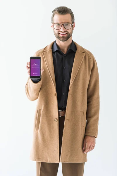 Homem bonito apresentando smartphone com aparelho instagram, isolado em branco — Fotografia de Stock