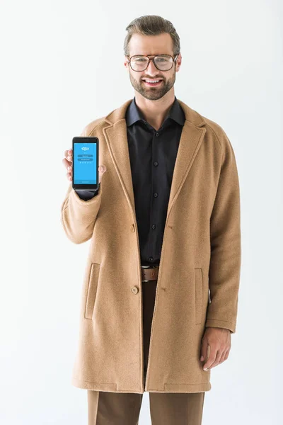 Hombre guapo presentando teléfono inteligente con dispositivo skype, aislado en blanco - foto de stock