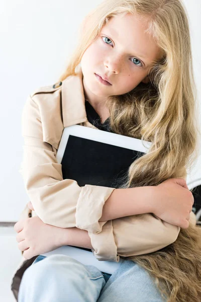 Beautiful child with long curly hair holding digital tablet and looking at camera on white — Stock Photo