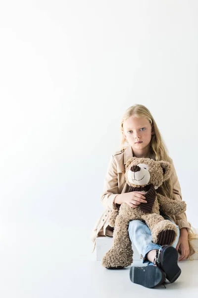 Full length view of beautiful stylish kid holding teddy bear and looking at camera isolated on white — Stock Photo