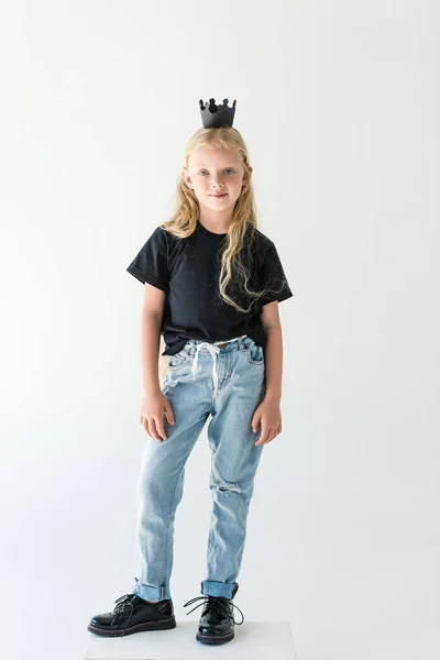 Beau gosse heureux avec de longs cheveux bouclés portant la couronne noire et souriant à la caméra isolé sur blanc — Photo de stock