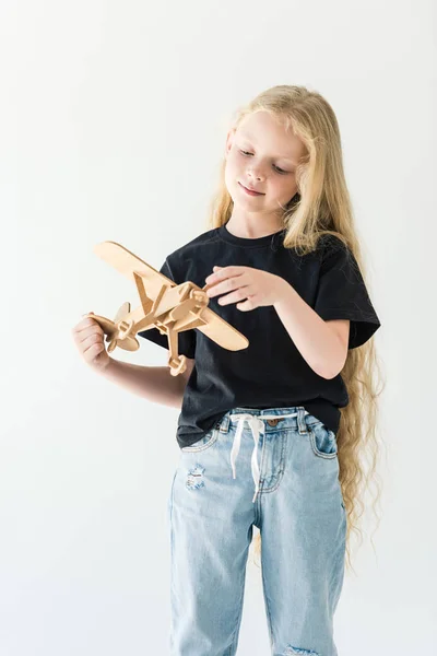 Adorable child with long curly hair playing with wooden toy plane isolated on white — Stock Photo