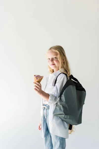 Cute little child with backpack eating tasty ice cream isolated on white — Stock Photo