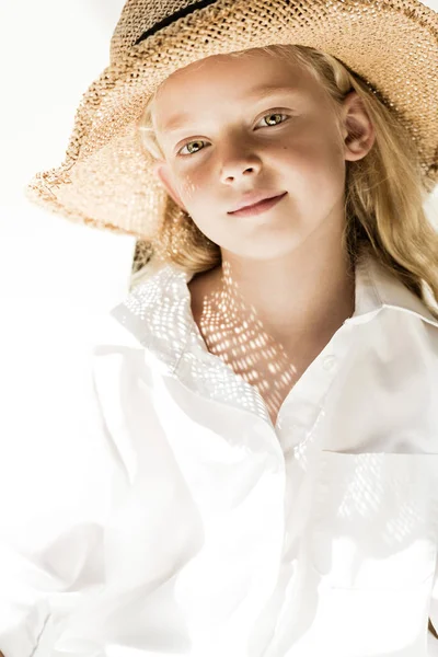 Portrait of adorable little child in wicker hat smiling at camera on white — Stock Photo