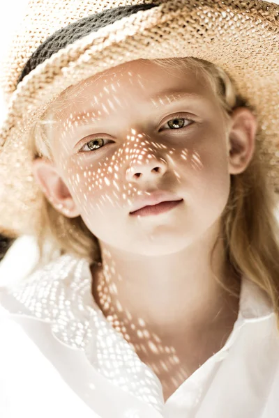 Крупным планом портрет очаровательного ребенка в плетеной шляпе, смотрящего в камеру — стоковое фото