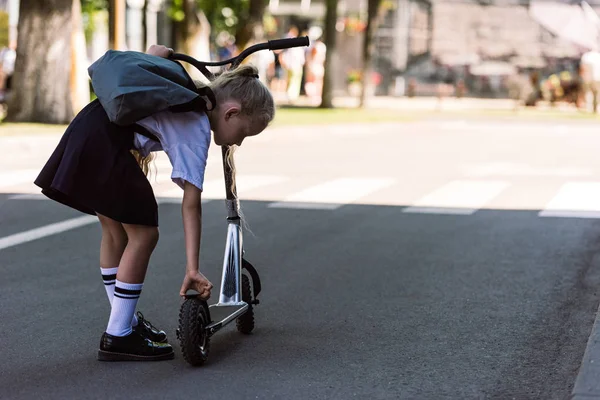 Vue arrière de mignon petit enfant avec sac à dos fixation scooter sur la rue — Photo de stock