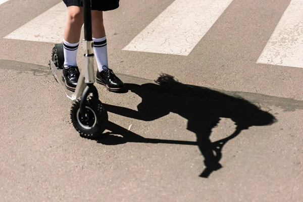 Низька секція маленької школярки, що їде скутер на вулиці — стокове фото