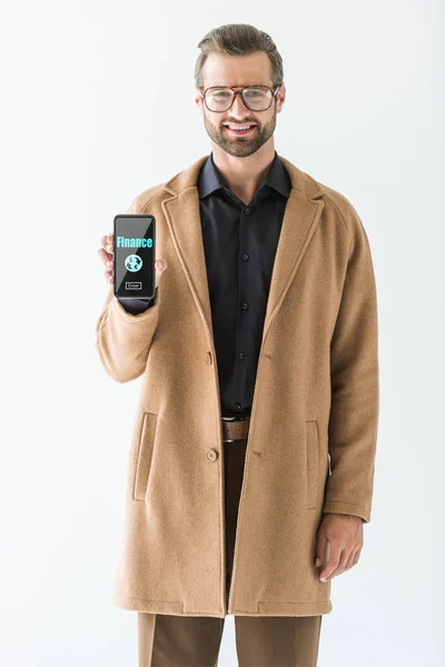 Smiling businessman presenting smartphone with finance icon on screen, isolated on white — Stock Photo