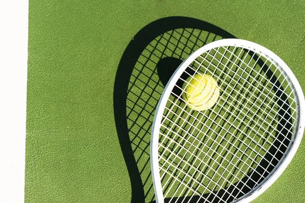 Vista superior de la raqueta de tenis y pelota acostado en la cancha de tenis verde - foto de stock