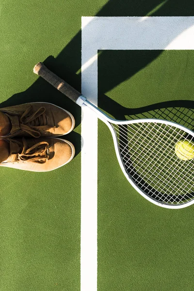 Vista parcial de la jugadora de tenis de pie cerca de la raqueta de tenis y pelota en la cancha — Stock Photo