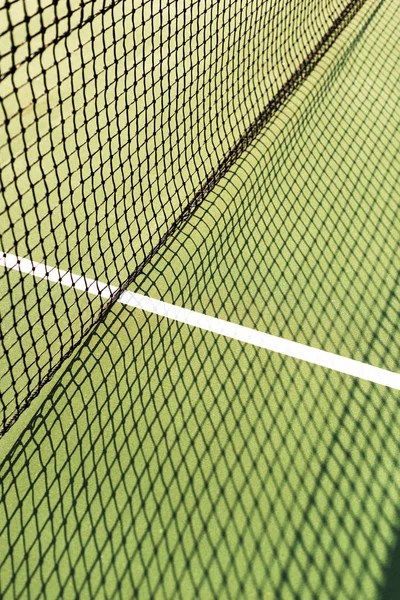 Закрыть вид на сетку с тенью на зеленом теннисном корте — стоковое фото