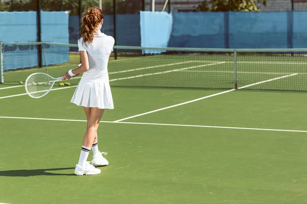 Vista posteriore della donna in uniforme da tennis bianca che gioca a tennis sul campo — Foto stock