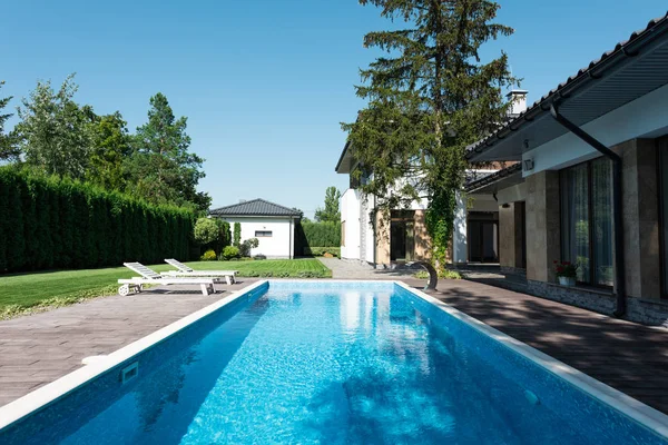 Vista para casa, jardim e piscina com espreguiçadeiras para relaxar — Fotografia de Stock
