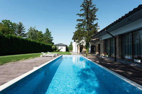 Vista de casa moderna, piscina con tumbonas - foto de stock