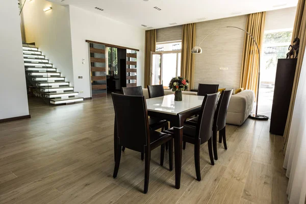 Vista interior del comedor moderno con mesa, sillas y escaleras - foto de stock