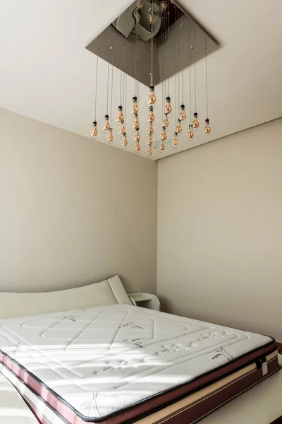 Interior of stylish bedroom with bed and light bulbs on ceiling — Stock Photo